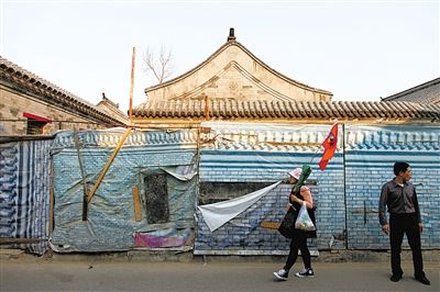 昨日，小石碑衚同，一位導(dǎo)遊帶著遊客走過建築圍擋。西城區(qū)今年計劃啟動什剎海舊城保護示範項目。新京報記者