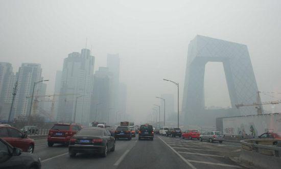 　　2月21日，車輛行駛在霧霾籠罩的北京街頭，中央電視臺(tái)新址大樓依稀可見。