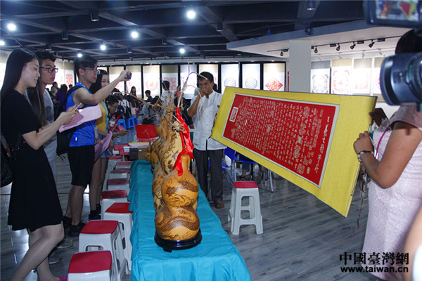 當?shù)胤俏镔|文化遺産代表性傳承人向學生展示用剪紙製作的王羲之《蘭亭集序》