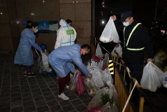 3月31日，在上海市中遠兩灣城小區(qū)，社區(qū)和街道幹部為封控樓棟居民送菜。新華社記者金立旺攝